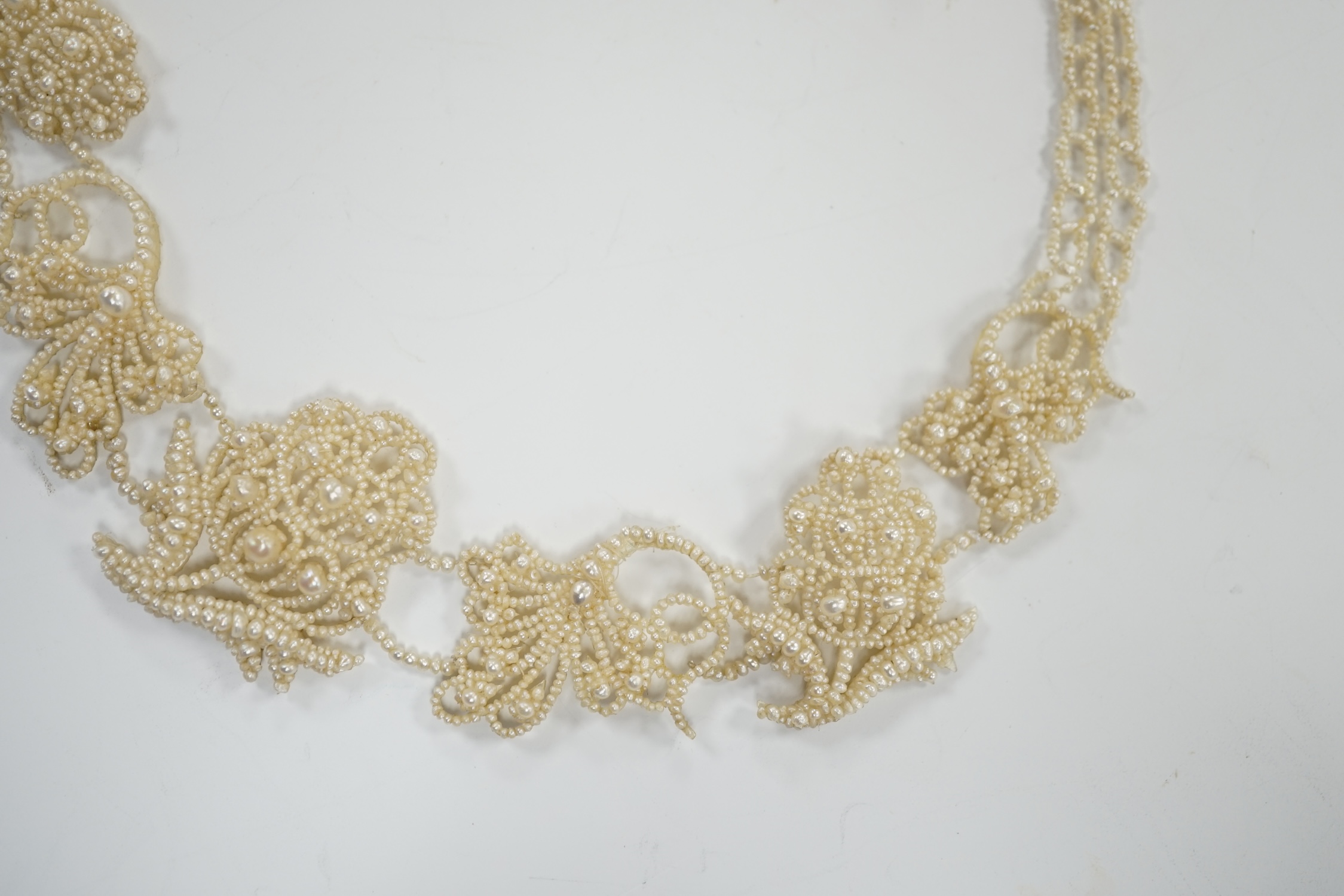 A cased Regency twin strand seed pearl choker necklace with scrolling floral motifs and yellow metal clasp, 34cm.